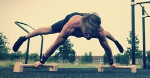 Dante Westerlaken is doing the straddle planche on wooden parallettes