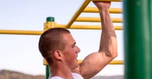 Strong man is doing a One Arm Pull-Up