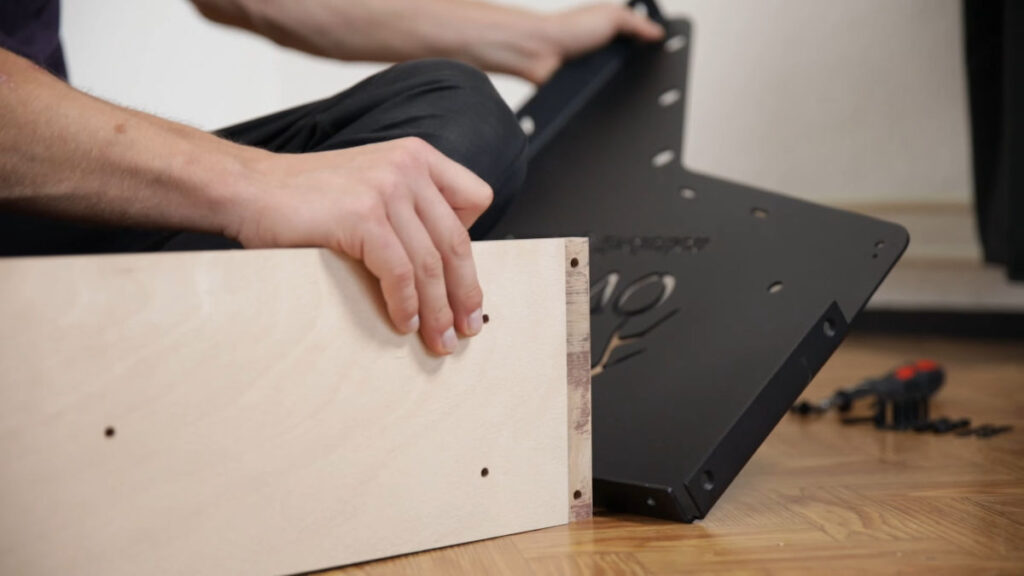 A side bracket of the clevo wall pull-up bar being fitted to the front plate for assembly.