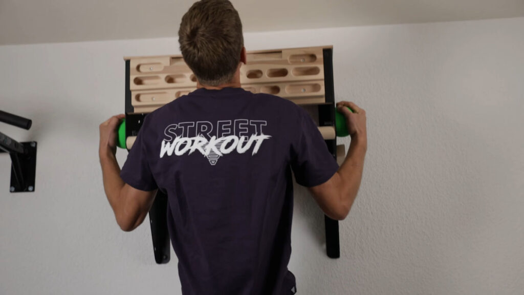 Jelle does a pull up holding on to the campus balls on either side of the clevo wall pull-up bar.