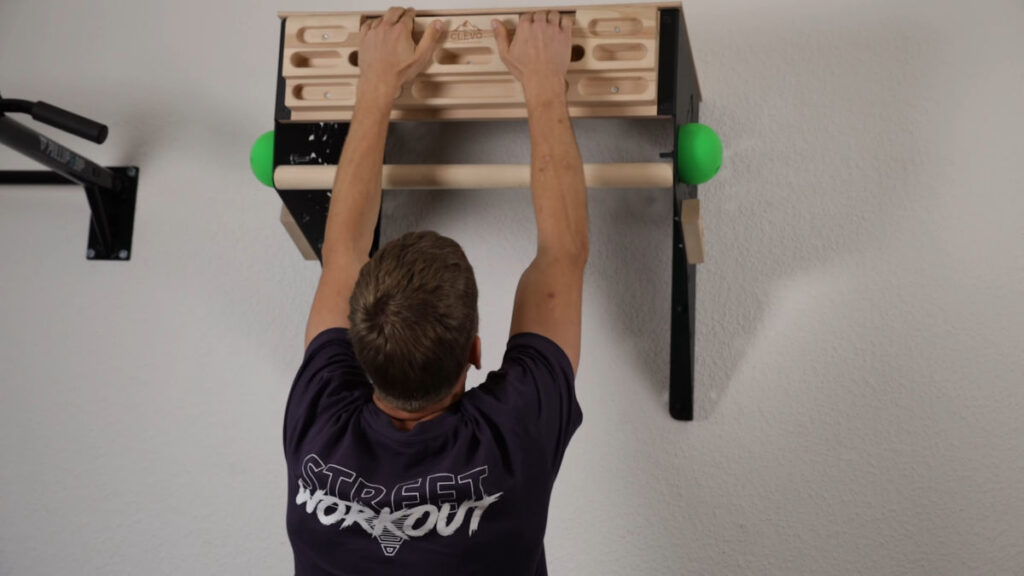 Jelle performs a dead hang using the slanted cuts of the clevo wall pull-up bar hangboard.