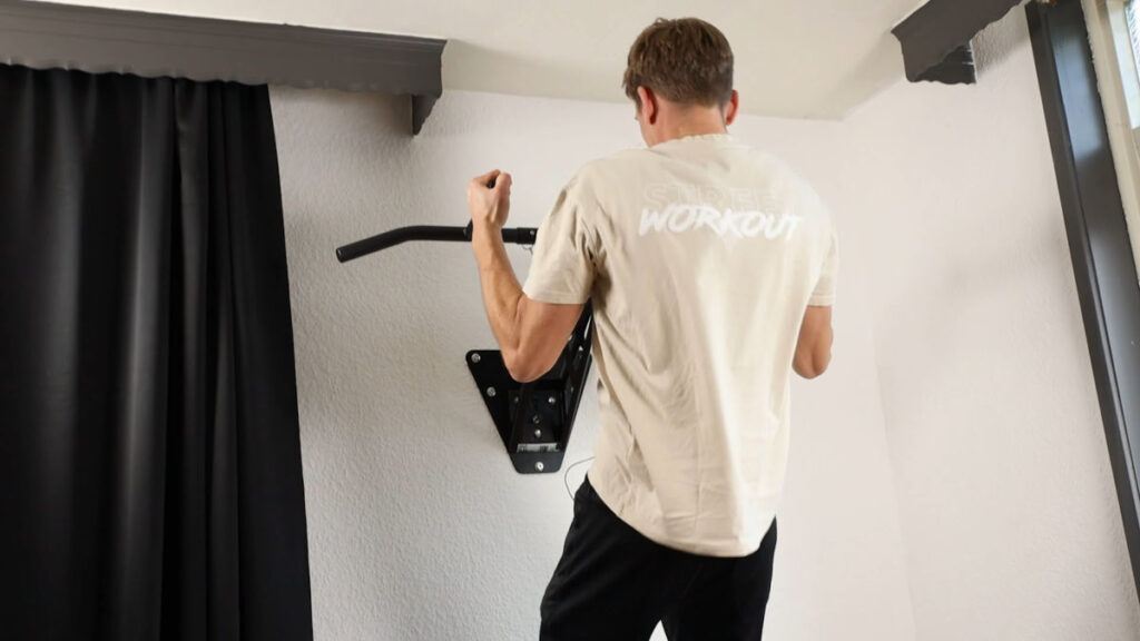 Man in white shirt with Workout printed on it performing a chin up with vertical grips on the Mobile Pullup and Dip Bar.