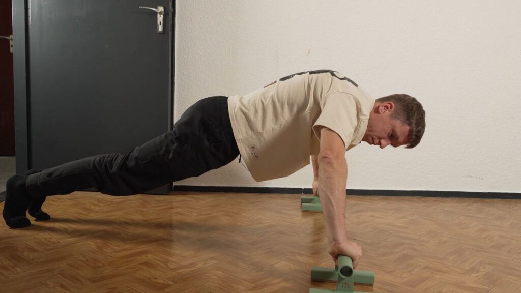 Man in white shirt peforming a push up on green Marmati cloud parallettes.