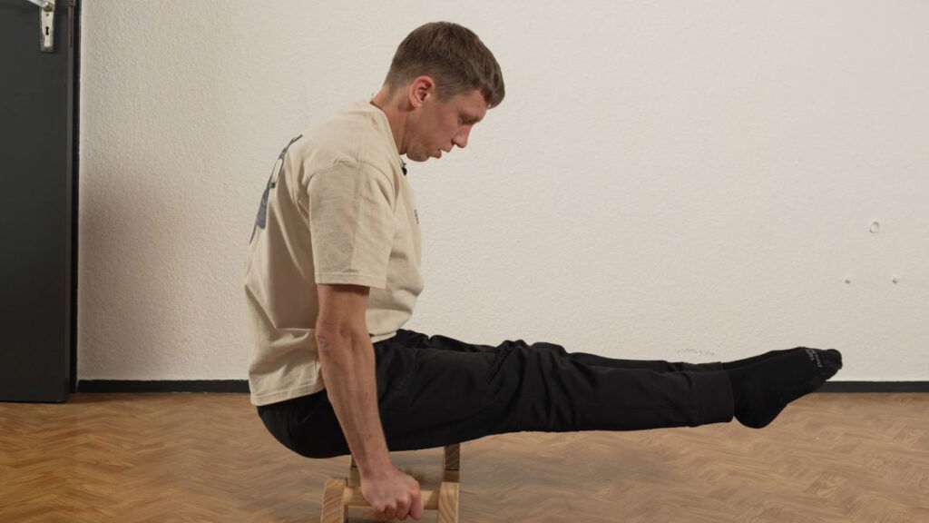 Man in white shirt performing an L-Sit on a pair of RaMaSS mini parallettes.