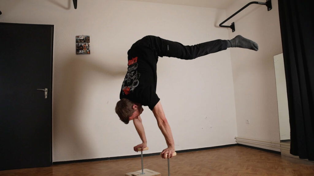 Man in black shirt performing a handstand on the Compact Gorletic Handstand Canes.