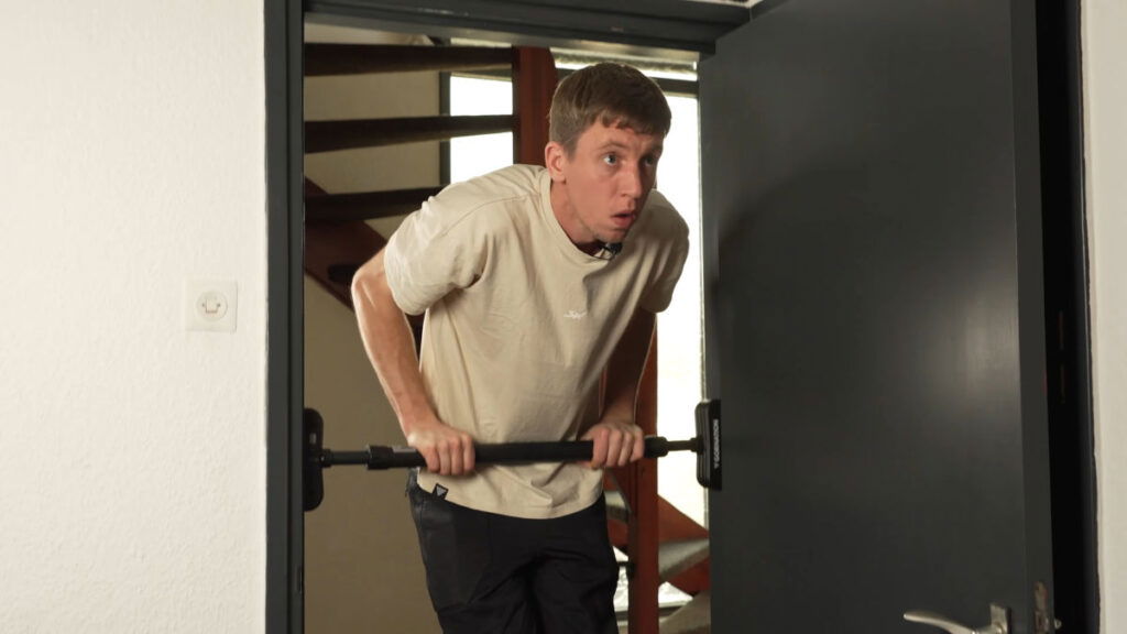 Man in white shirt performing a straight bar dip on the Gornation Pull-Up Bar "Extend-It" in a doorway.