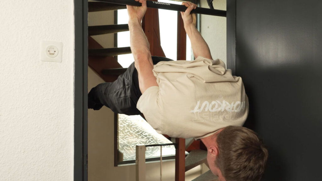 Man in white short performing a back lever on the Gornation Pull-Up Bar "Extend-It" in a doorway.