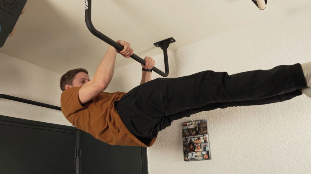 Man in brown shirt performing a front lever on the Gornation Pull-Up Bar "Multi" mounted to a ceiling.