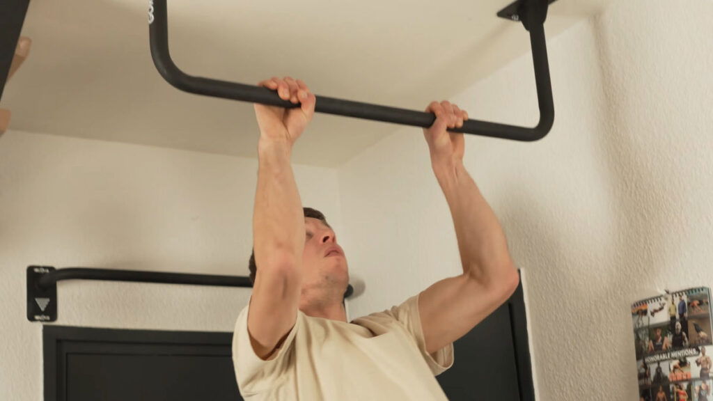 Man in white shirt performing a Pull-Up on the Gornation Pull-Up Bar "Multi" mounted on a ceiling.