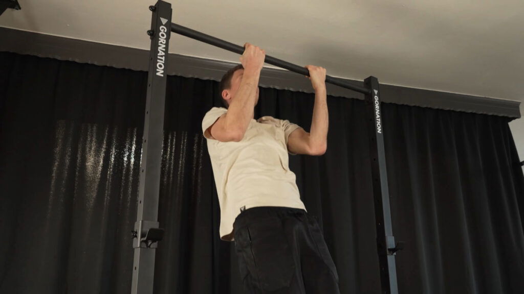 Man in white shirt performing a Chin-Up on a Gornation Pull-Up Station, the Gornation Pull-Up Bar being extended to its maximum height.