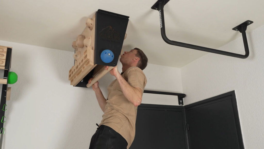 Man in beige shirt doing a Pull-Up on the CLEVO Ceiling M Pull-Up Bar and Hang Board