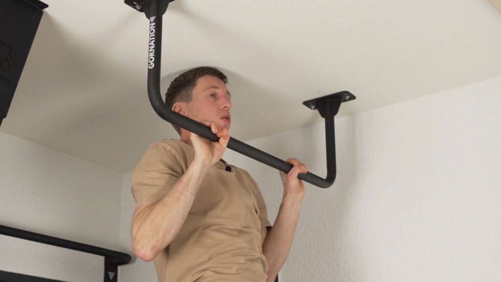 Man in beige shirt performing a full range of motion Pull-Up on the GORNATION Ceiling Pull-Up Bar.