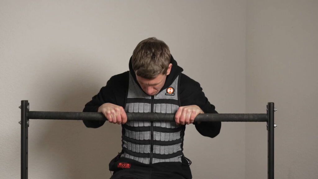 Man doing a bar muscle up while wearing the Hyperwear Hyper Vest Pro.