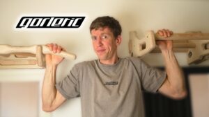 Man in grey shirt hanging off two gornation wooded pull-up bars.