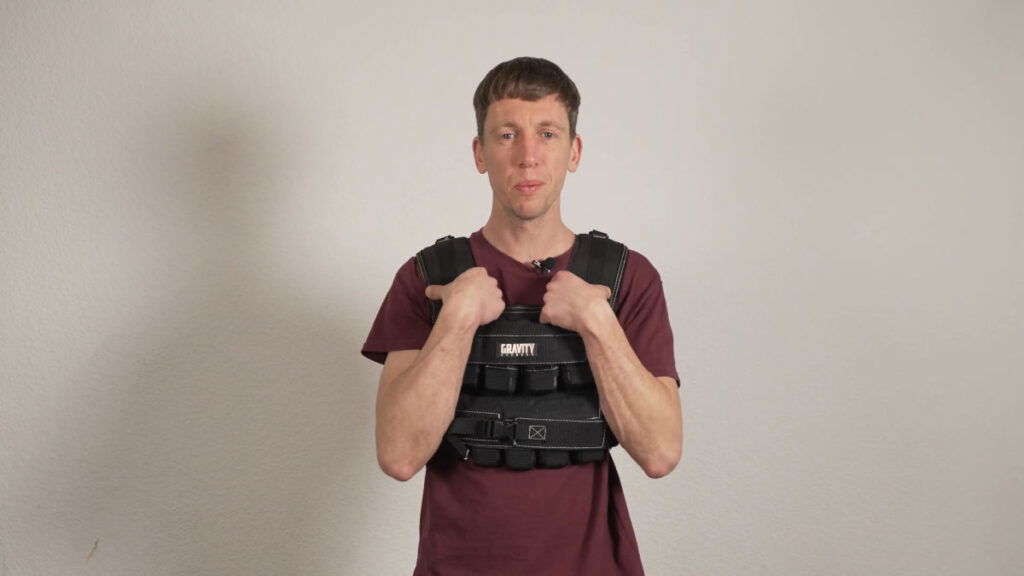 Man in red shirt wearing the Gravity Fitness Weighted Vest of 20kg and looking comfortable in it.