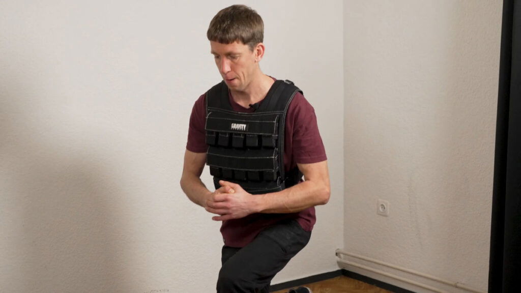 Man in red shirt doing lunges while wearing the Gravity Fitness Weighted Vest of 30kg.