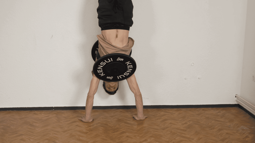 Man performing a handstand while wearing the Kensui EZ vest plate loaded weight vest.