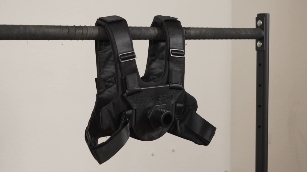 Example of a plate loaded weight vest, the Kensui EZ Vest hanging on a dip bar with its attachment point still empty.