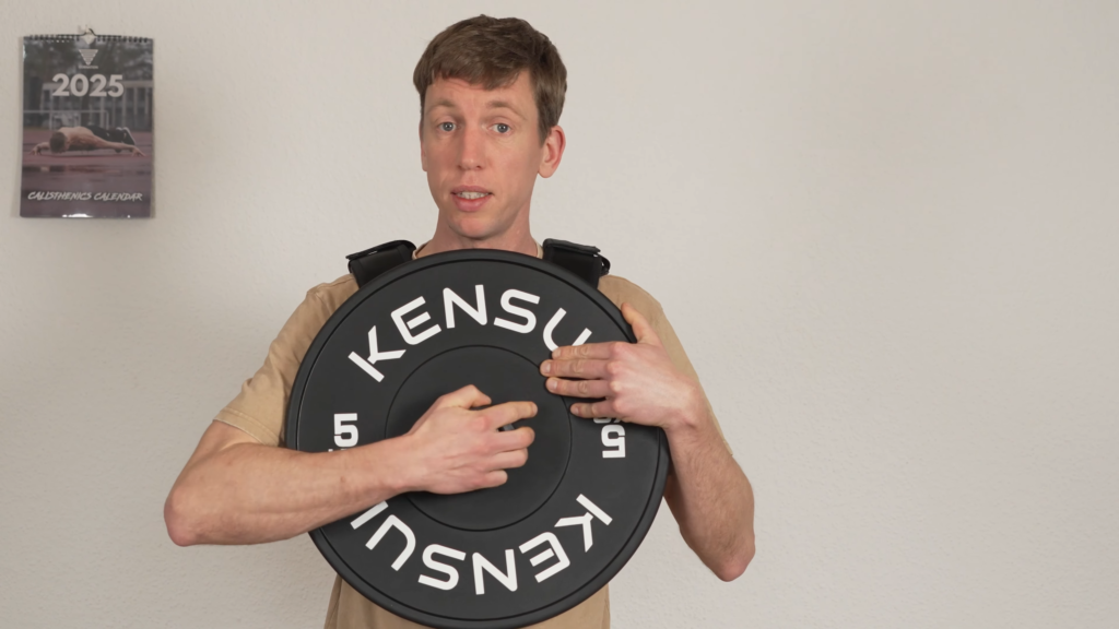 Man showing the large diameter of the plate on his Kensui EZ Vest plate loaded weight vest. He has to reach around the large plate to touch the front.