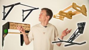 Man in white shirt looking searchingly between a collage and different wall pull-up bars.