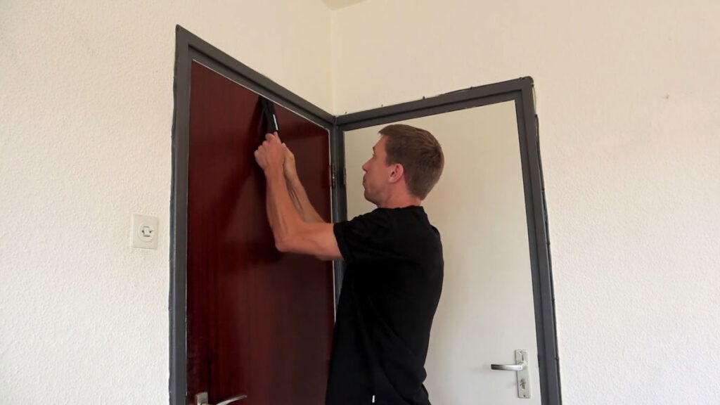 Man inspecting the straps on a Gornation door anchor attached to a closed door.
