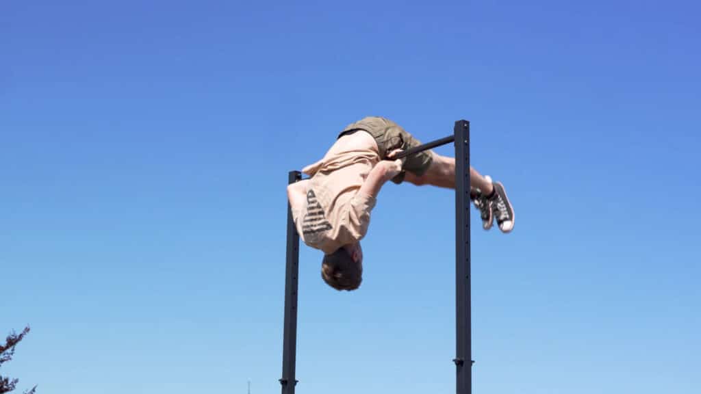 Man in beige shirt doing a rollover on the barmania pro Free-Standing Pull-Up Bar.