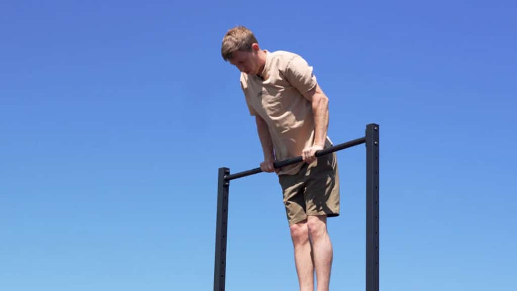 Man in beige shirt doing a muscle-up on the barmania pro Free-Standing Pull-Up Bar.