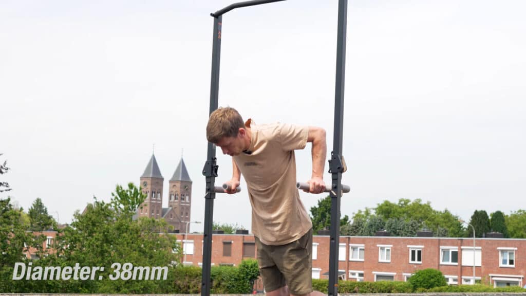 Man in beige shirt doing dips on the dip handles of the BullBar Free-Standing Pull-Up Bar.