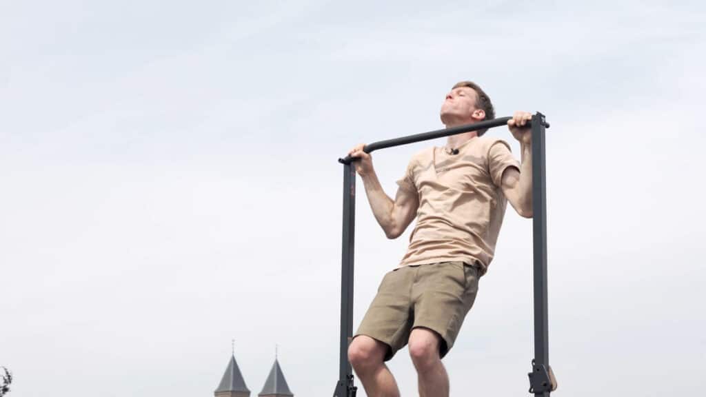 Man in beige short doing wide pull-ups on the BullBar Free-Standing Pull-Up Bar.
