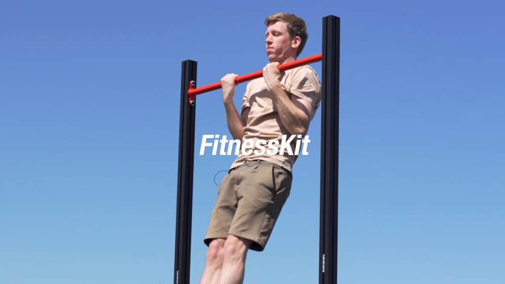 Man in beige shirt and brown shorts doing a chin-up on the FitnessKit modular pull-up bar.