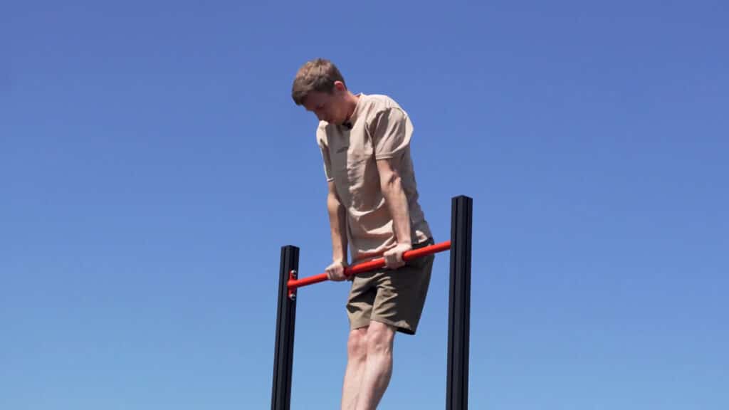 Man in beige shirt doing a muscle-up on the FitnessKit Modular Pull-Up Bar.