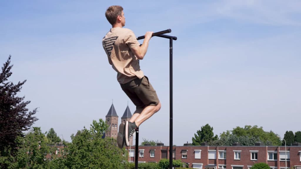 Man in beige shirt doing a pull-up on the Gravity Fitness Free-Standing Pull-Up Bar