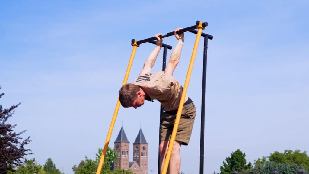 Man in beige shirt doing a skin-the-cat on the Gravity Fitness Free-Standing Pull-Up Bar.