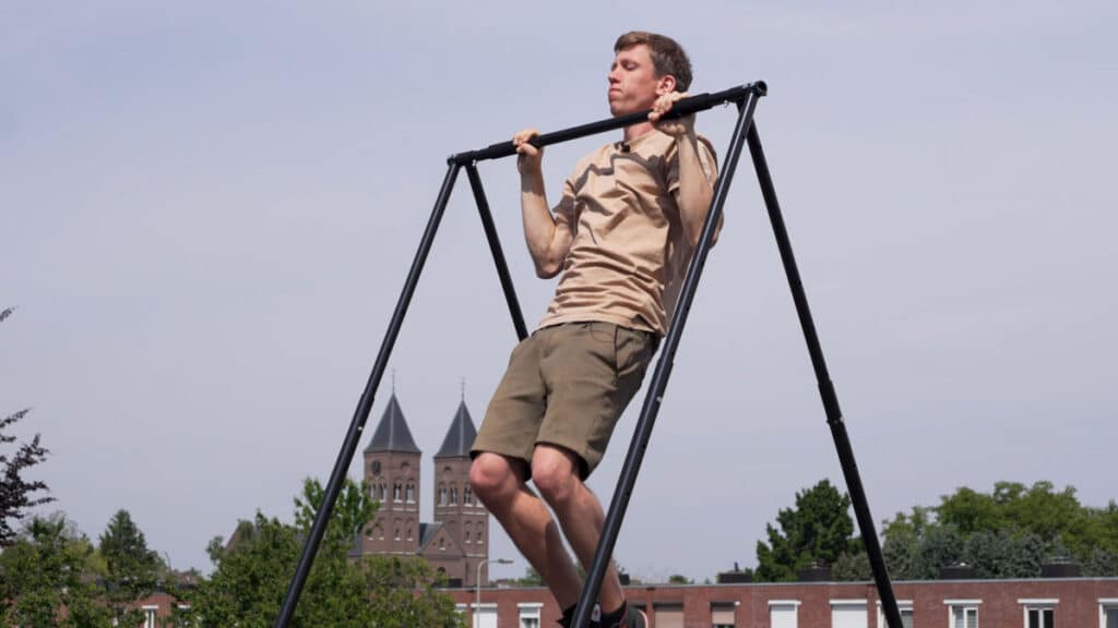 Man in beige shirt doing a pull-up on the Khanh Trinh Foldable Free-Standing Pull-Up Bar/