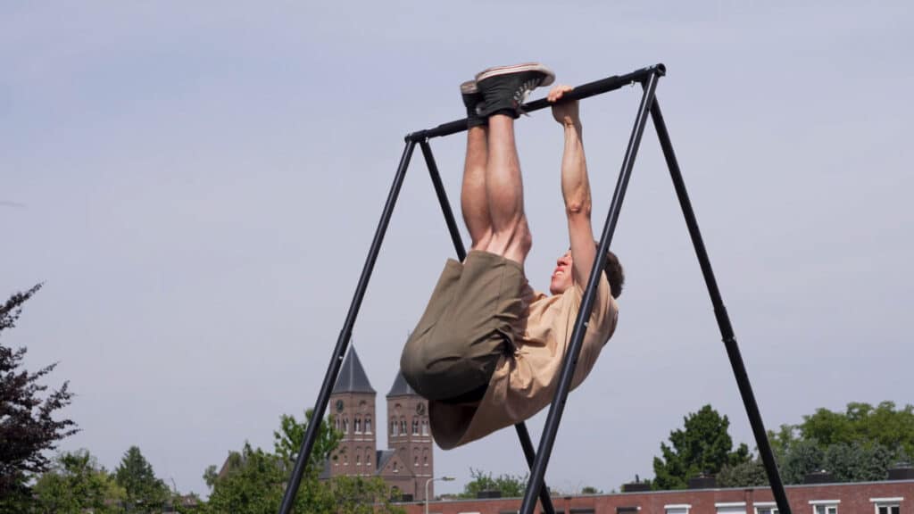 Man in beige shirt doing leg raises on the Khanh Trinh Free-Standing Pull-Up Bar.
