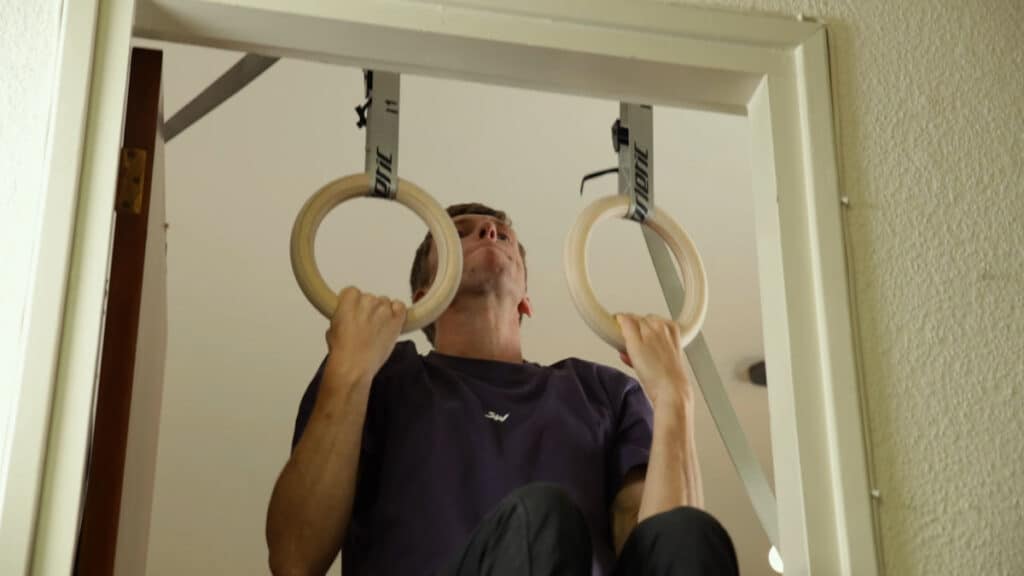 Man in violent shirt performing Chin-Ups on the Gorletic Gymnastic Rings.