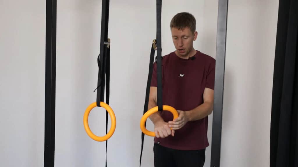 Man in purple shirt inspecting and feeling the texture on the Nayoya Gymnastic Rings.