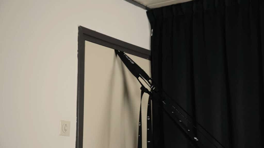 The door anchor belonging to the Pullup & Dip Gymnastic Rings in use, the straps pulled taut by an exercises off screen.
