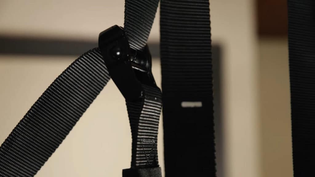Close up of the black powder-coated buckle of the Pullup & Dip Gymnastic Rings with the strap pulled through it.