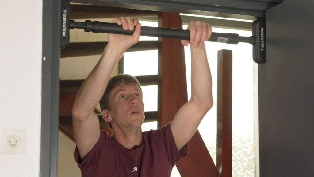 Man in purple shirt fastening a Gornation Extend-It Doorway Pull-Up Bar as his home Pull-Up Bar.