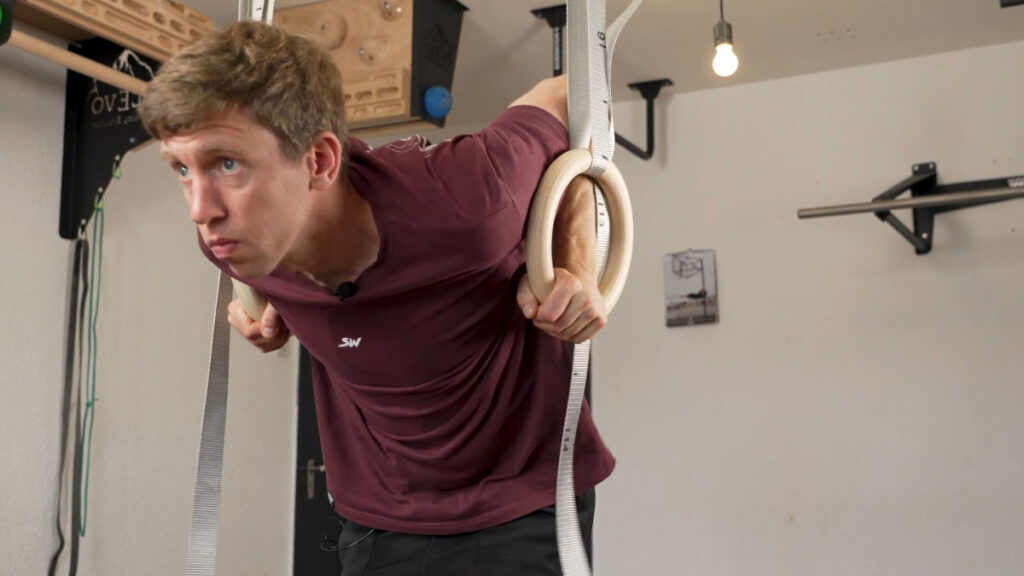 Man in purple shirt doing a ring muscle-up on a set of Gorletic Gymnastic rings.