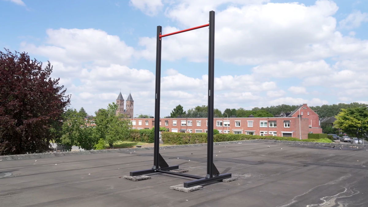 The FitnessKit Basic Strength Bar standing outside on a roof with a church in the background.