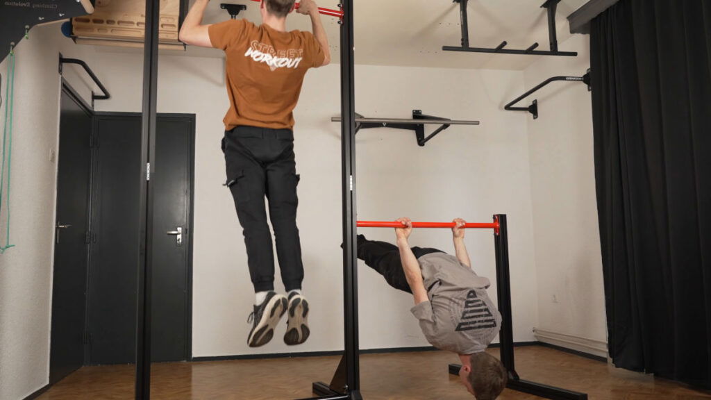 A FitnessKit Basic Strength Bar paired with an added Basic Strength Static Bar as one complete unit, both in use by men performing Calisthenics.