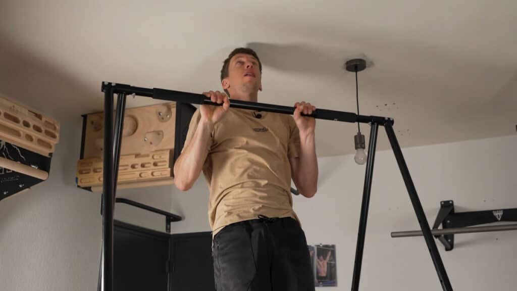Man in beige shirt completing a Pull-Up on the Khanh Trinh Pull-Up Bar.