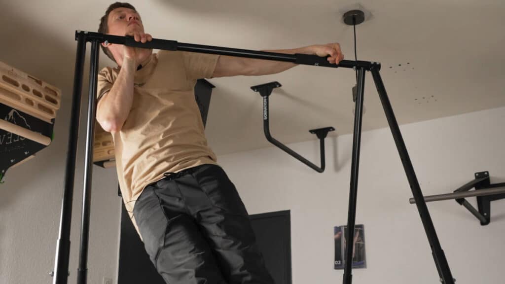 Man in beige shirt performing Archer Pull-Ups on the Khanh Trinh Pull-Up Bar, testing its side-to-side stability.
