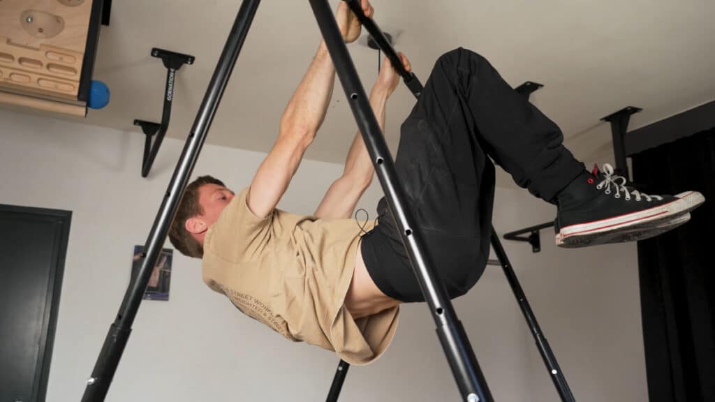 Man in beige shirt performing a skin-the-cat on the Khanh Trinh Pull-Up Bar.