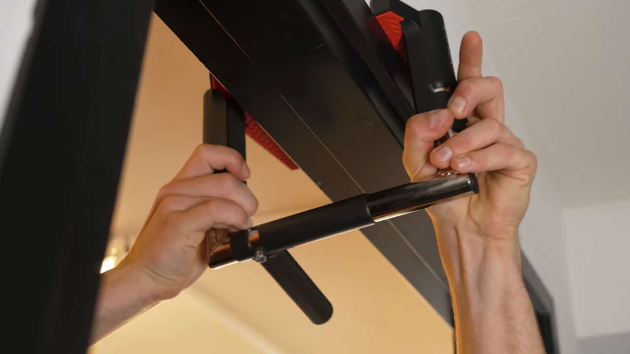 Man attaching the Jayflex CrossGrips door Pull-Up Handles to a door frame.