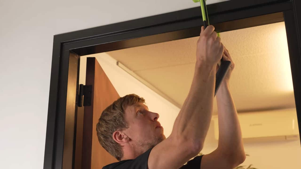 Man attaching the Duonamic Eleviia door Pull-Up Handles to a door frame.