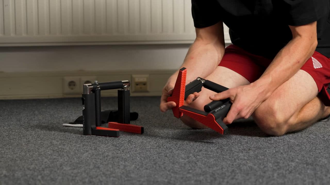 Man in red shorts folding up the Jayflex CrossGrips door pull-up handles.