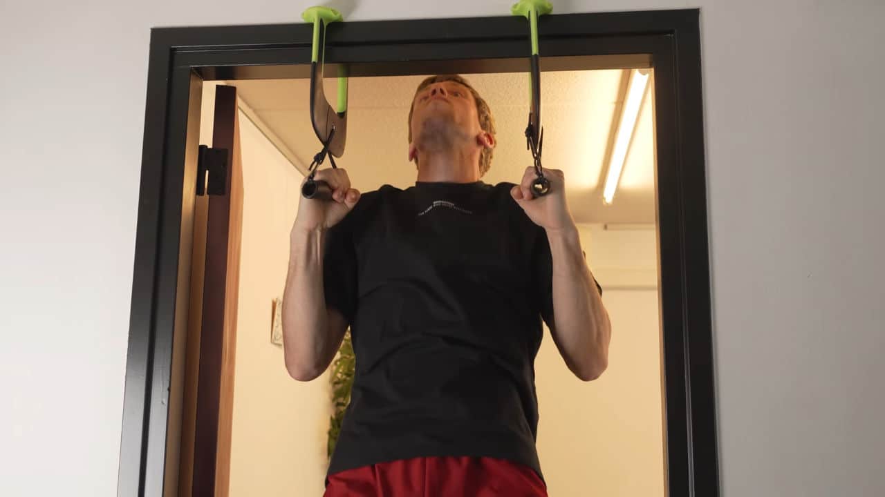 Man in black shirt performing neutral grip pull-ups on the duonamic eleviia door pull-up handles.